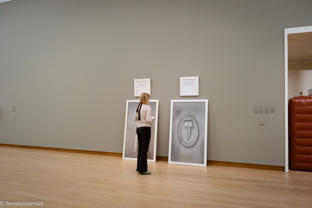 Visitor looking at two large framed prints leaning against the gallery wall