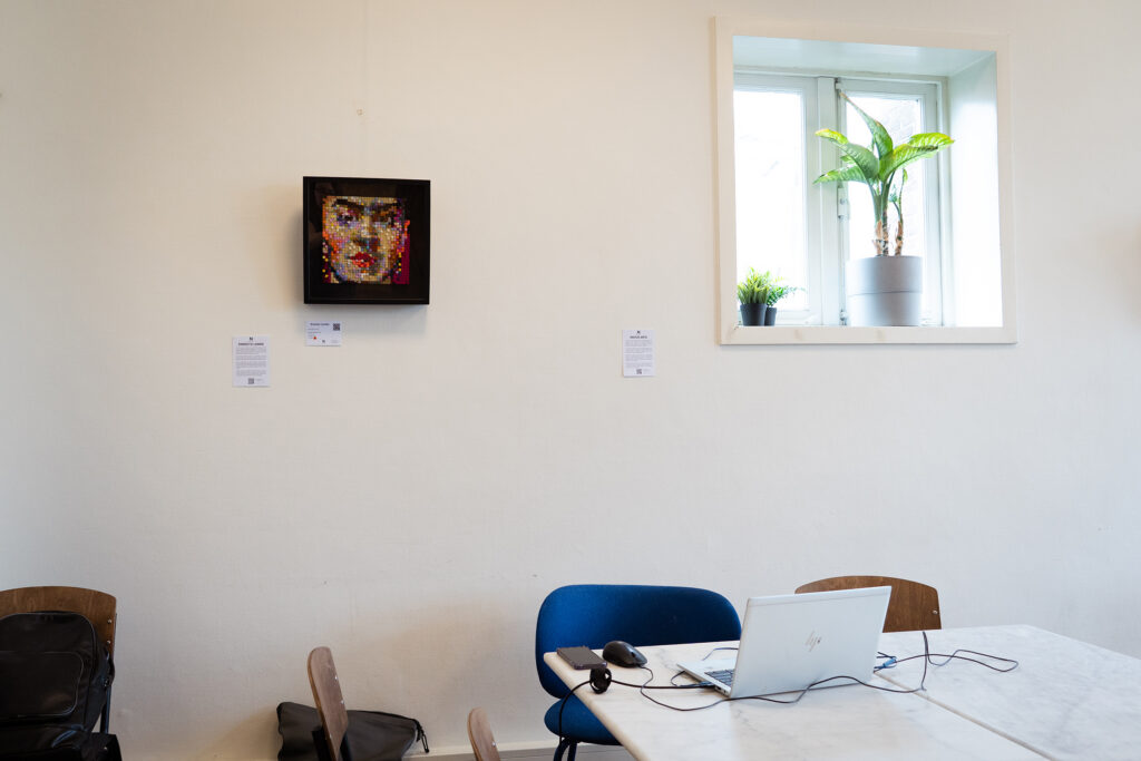 Colourful mosaic portrait hanging on an office wall above a desk