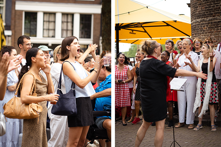 Choir in red and white singing outdoors while a crowd claps along