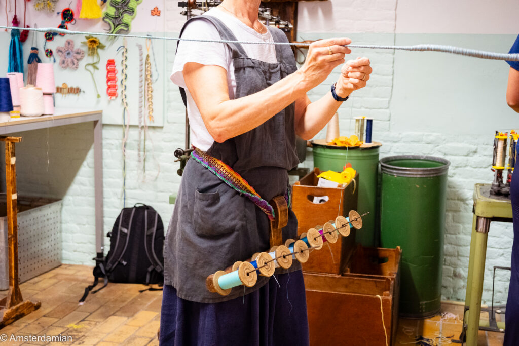 A maker winding yarn onto wooden bobbins in the workshop at the TextielLab, Tilburg