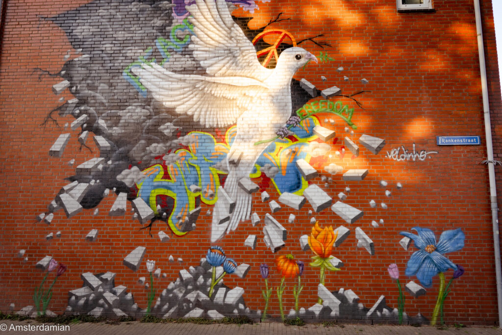 Mural of a white dove breaking through a brick wall, with flowers, on Rankenstraat in Tilburg