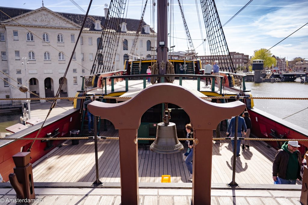 Ship's bell on the deck of the Amsterdam, with the maritime museum behind