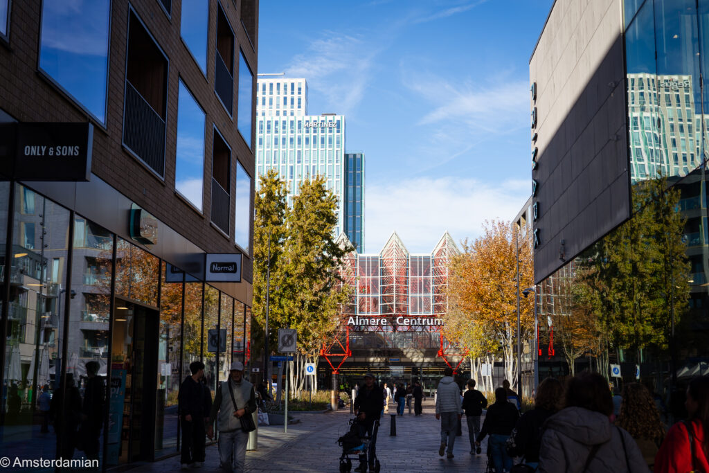 Shoppers on a street leading to Almere Centrum station, with towers behind
