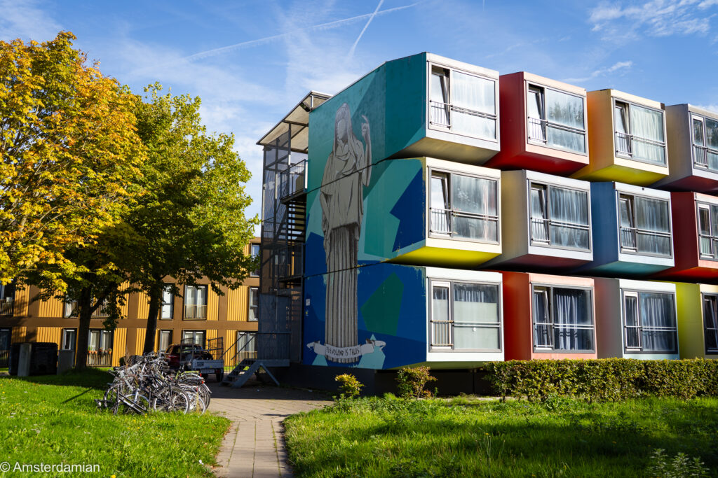 Colourful homes with a large mural of a robed figure in Almere