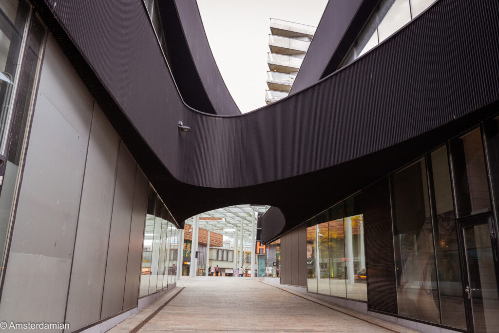 Curving black façade over a walkway in Almere city centre