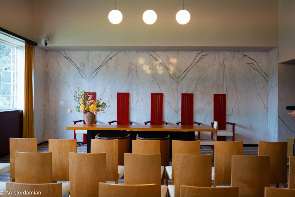 Marble wall and red high-backed chairs in a room of the Raadhuis Hilversum