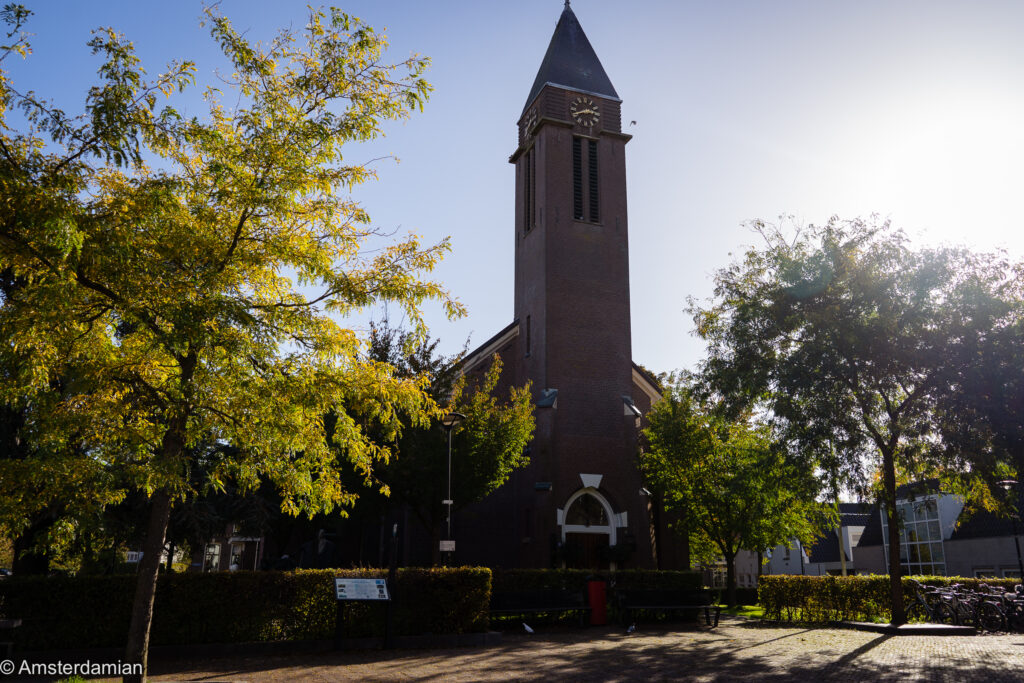 Brick church tower framed by autumn trees in Amstelveen's Oude Dorp